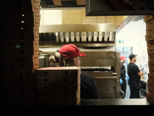 Pizzaria com equipe e pilhas de caixas em alta demanda